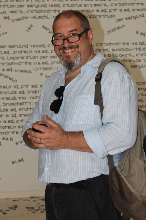 Ritratto di Guido Silipo, sorridente, con occhiali e zaino a tracolla